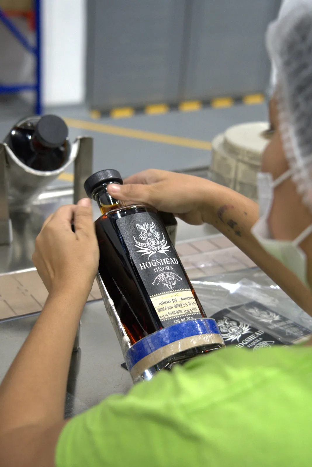 A capsule being sealed over the neck of a filled Hogshead Travesía bottle