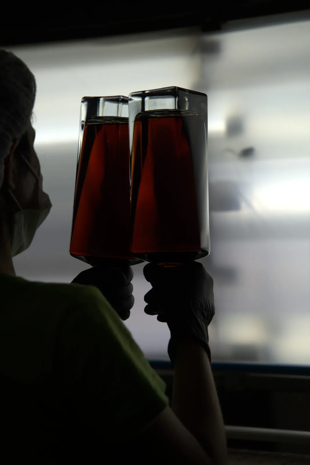 Two filled bottles held up against a bright inspection light