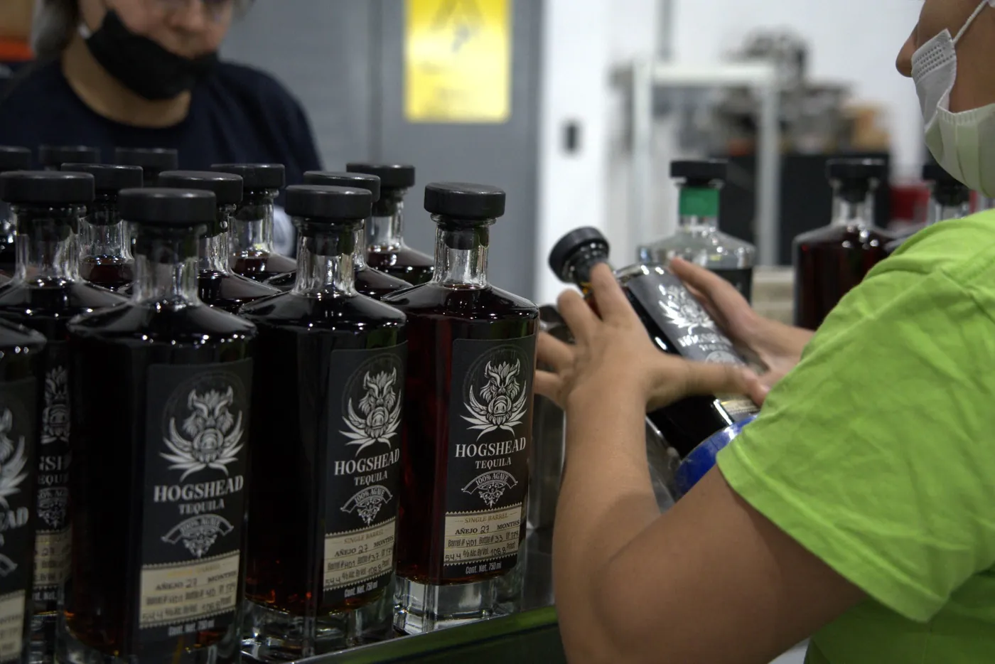 Rows of labelled Hogshead Travesía bottles being finished by hand, each label hand-written with its barrel and bottle number